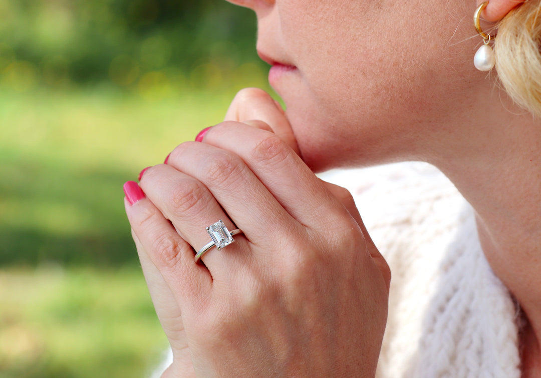 Bague solitaire L'exquise coupe émeraude en or blanc sur main de coté – Flamme en Rose