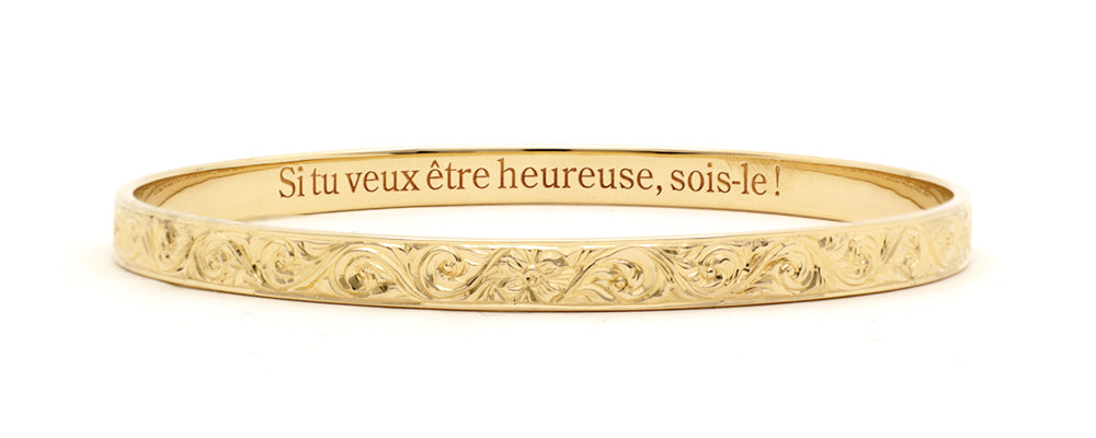 Bracelet jonc en or jaune gravé, orné de motifs floraux ciselés à la main, avec une inscription intérieure : « Si tu veux être heureuse, sois-le ! » – bijou raffiné signé Flamme en rose.