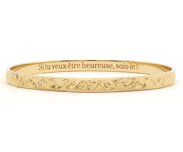 Bracelet jonc en or jaune gravé, orné de motifs floraux ciselés à la main, avec une inscription intérieure : « Si tu veux être heureuse, sois-le ! » – bijou raffiné signé Flamme en rose.