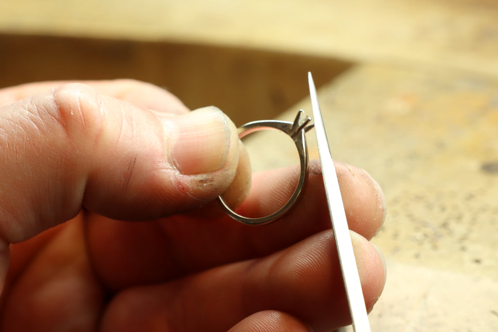 Joaillier limant une bague en or lors d'une réparation en atelier.