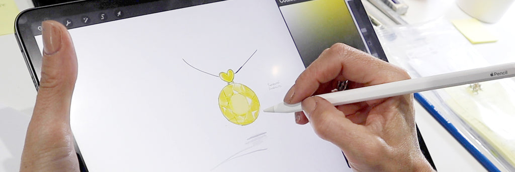 Croquis de bijou réalisé sur tablette numérique à l’aide d’un stylet, illustrant un pendentif rond en or jaune au cœur d’un processus de création sur mesure.